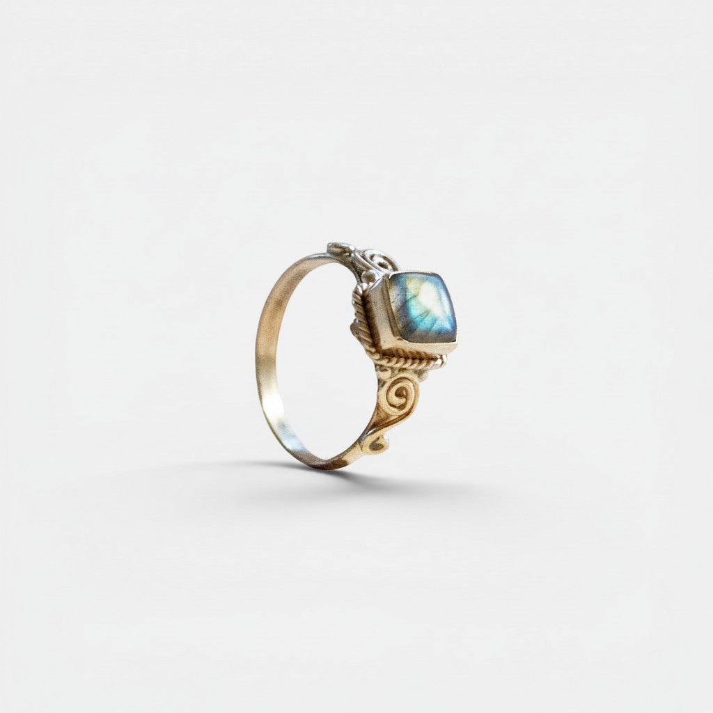 Nooe UG rectangular labradorite ring in brass with playful swirling details and a shimmering blue-green stone.