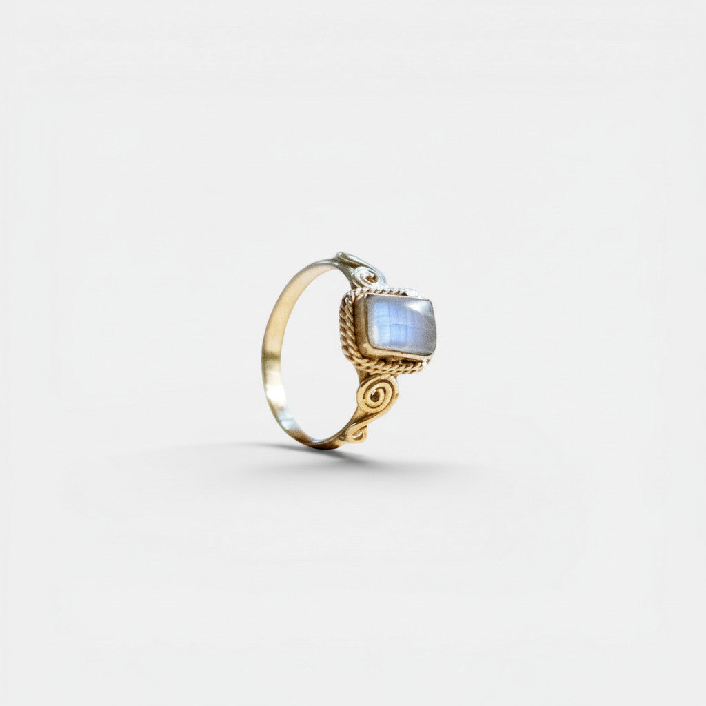 Nooe UG handmade brass ring with a square cut moonstone in white and blue hues, featuring elegant spiral details.
